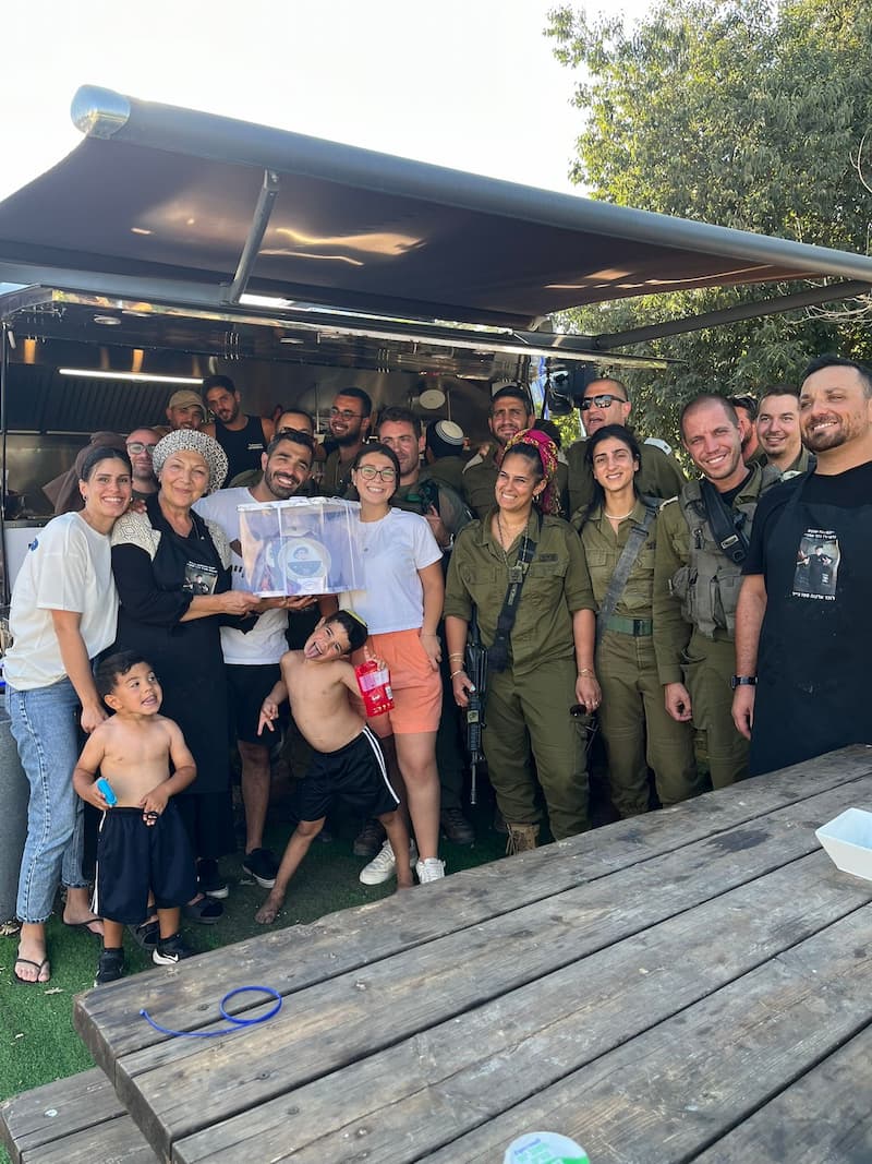 תמונה קבוצתית ליד הפודטראק: מתנדבים, חיילות וחיילים וילדים מחייכים יחד