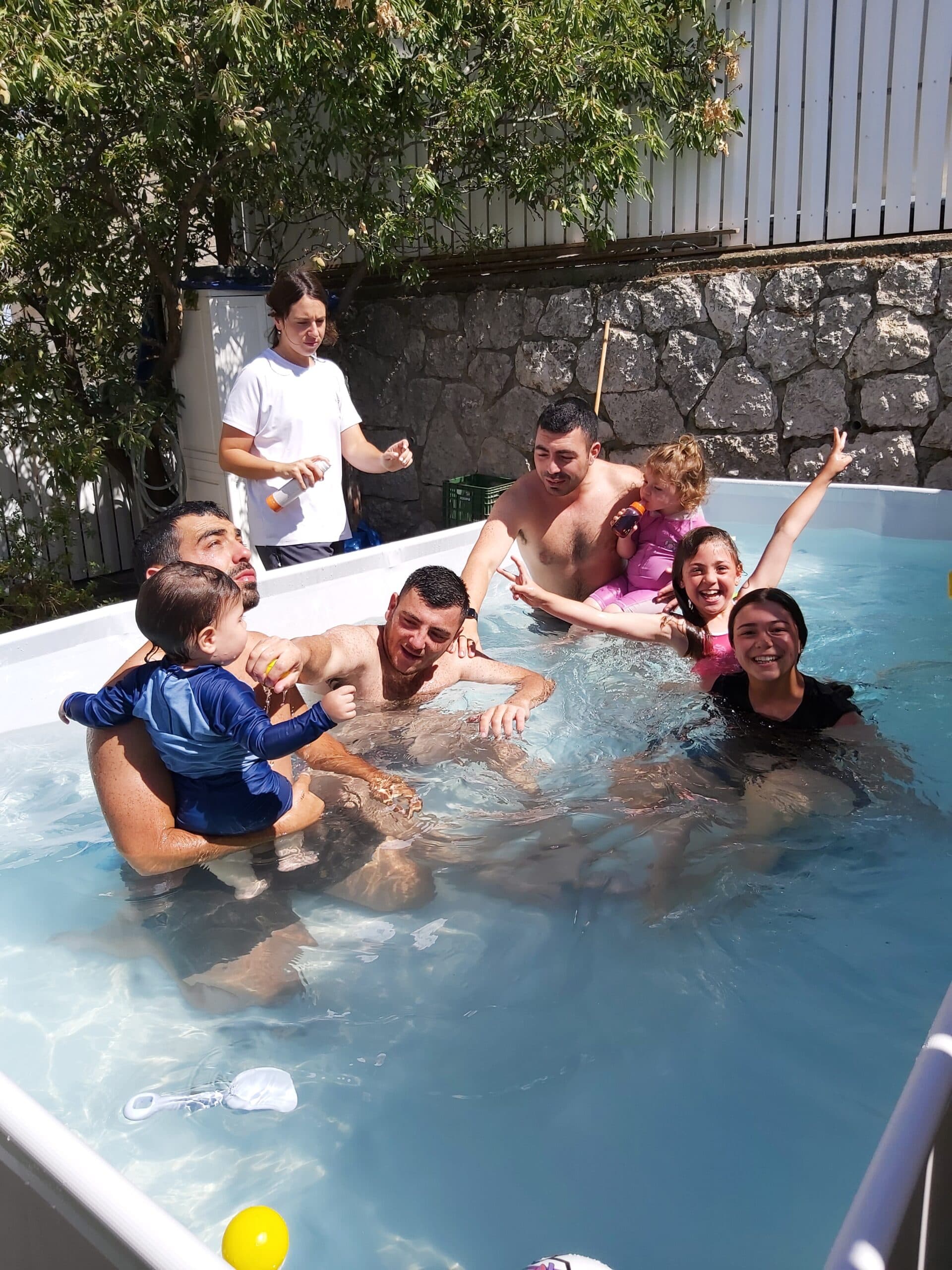 Un groupe de jeunes et d’enfants s’amusent ensemble dans une piscine de jardin